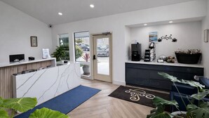 A reception area with a marble counter, a coffee machine, and a potted plant.