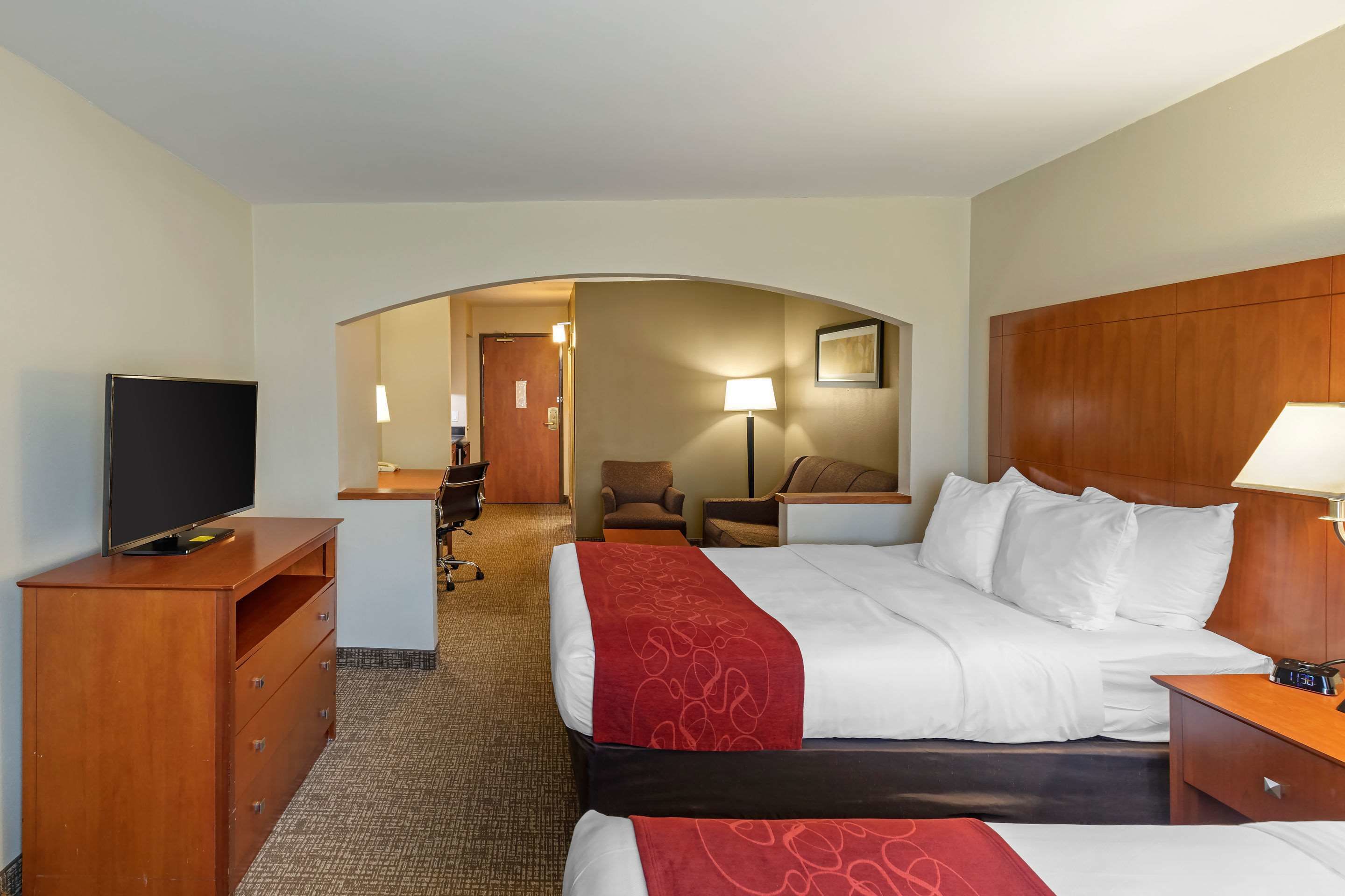 Habitación de hotel con una cama grande, televisor, escritorio con lámpara y una silla.