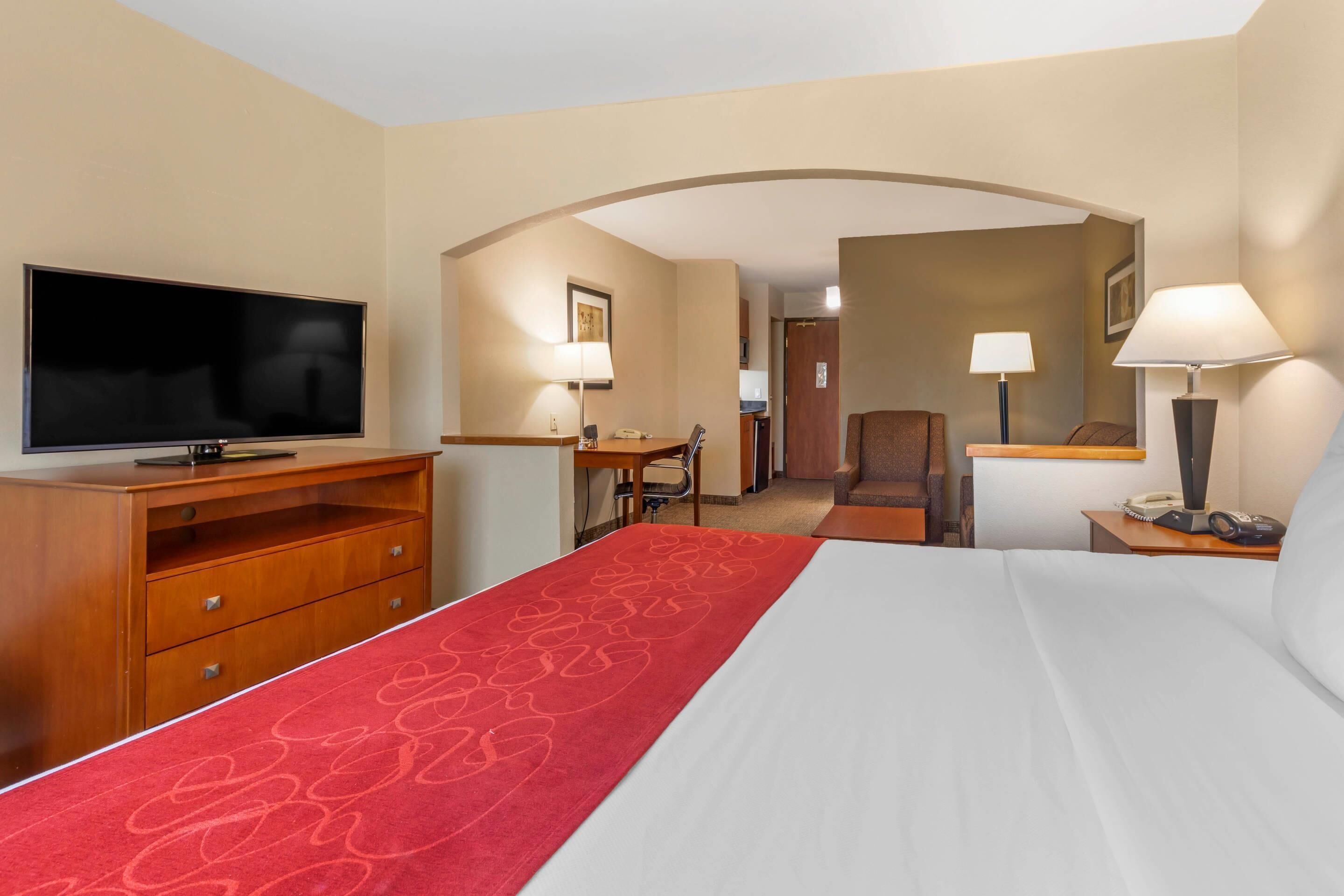Een hotelkamer met een bed, een televisie, een bureau, een stoel, een lamp en een telefoon.