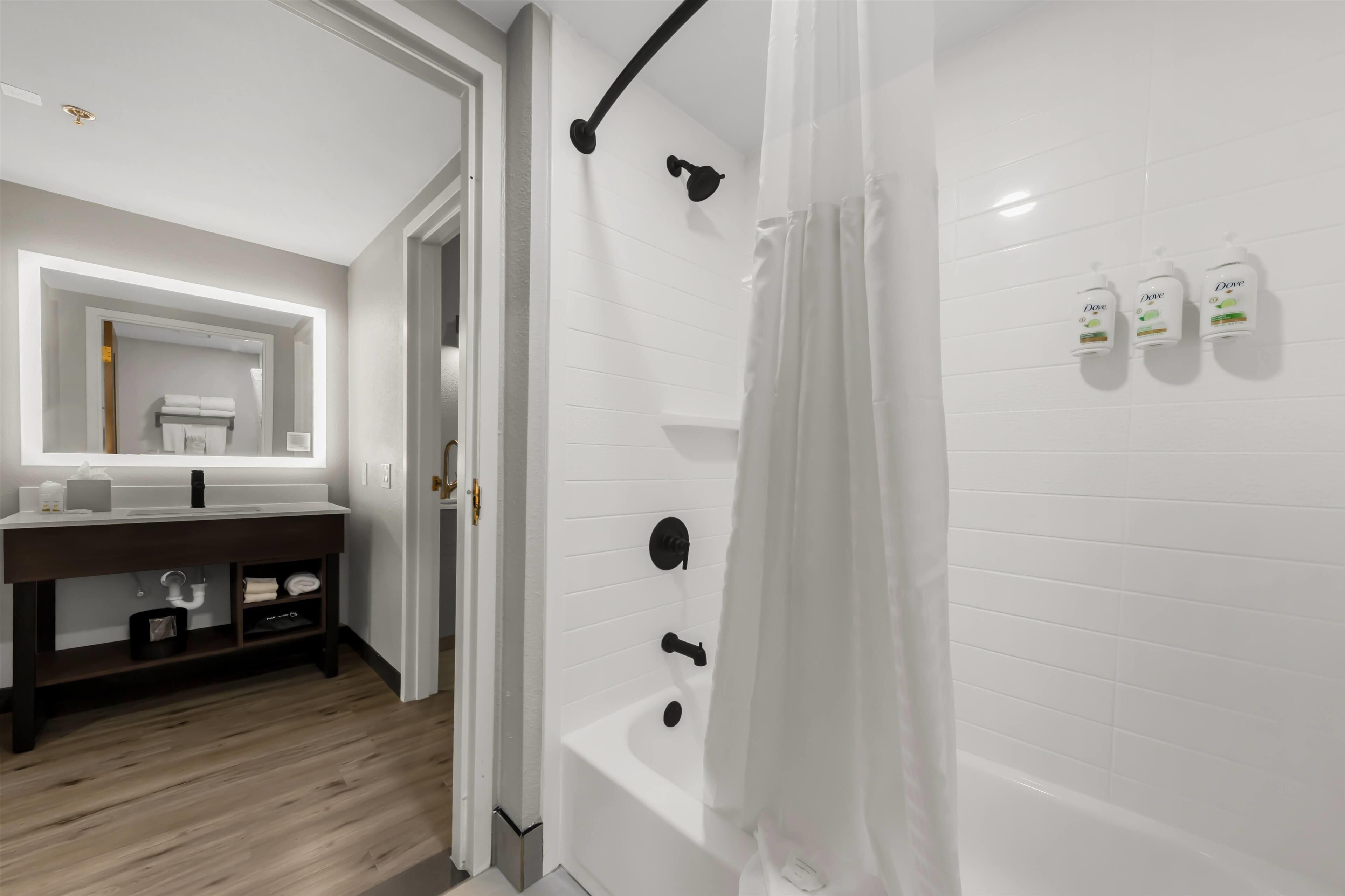 A modern bathroom with a bathtub, a vanity with a mirror, and a shower curtain.