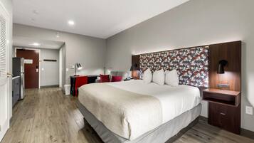 A modern hotel room with a large bed, a desk, and a wardrobe.