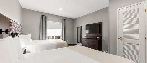 A hotel room with two beds, a TV, a wardrobe, and a door with a louvered design.