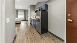 Una cocina moderna con armarios oscuros, un refrigerador de acero inoxidable y una ventana con cortinas.