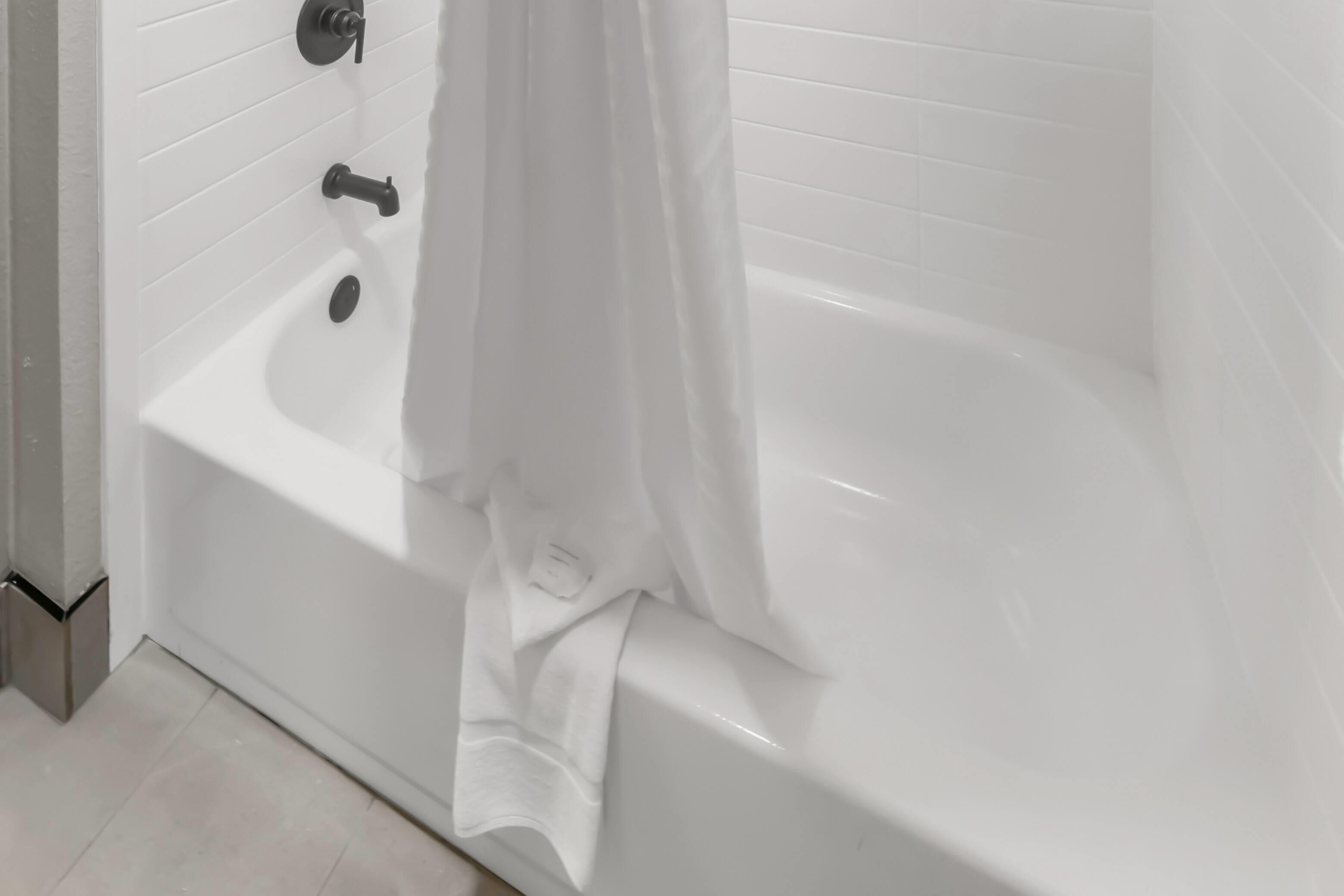 Una bañera blanca con cortina de ducha, grifo y desagüe.