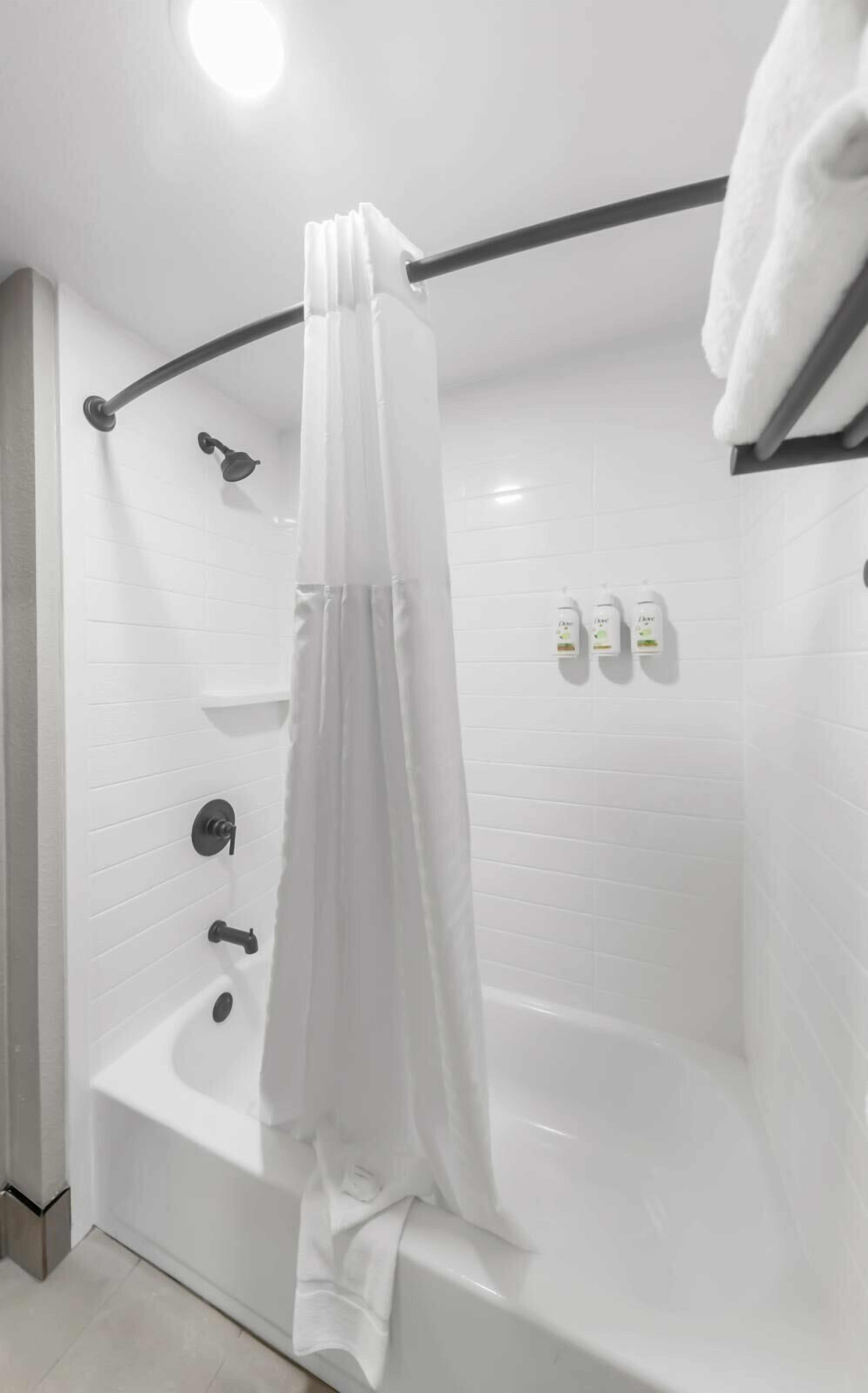 A modern bathroom with a white bathtub, a shower curtain, and a towel rack.