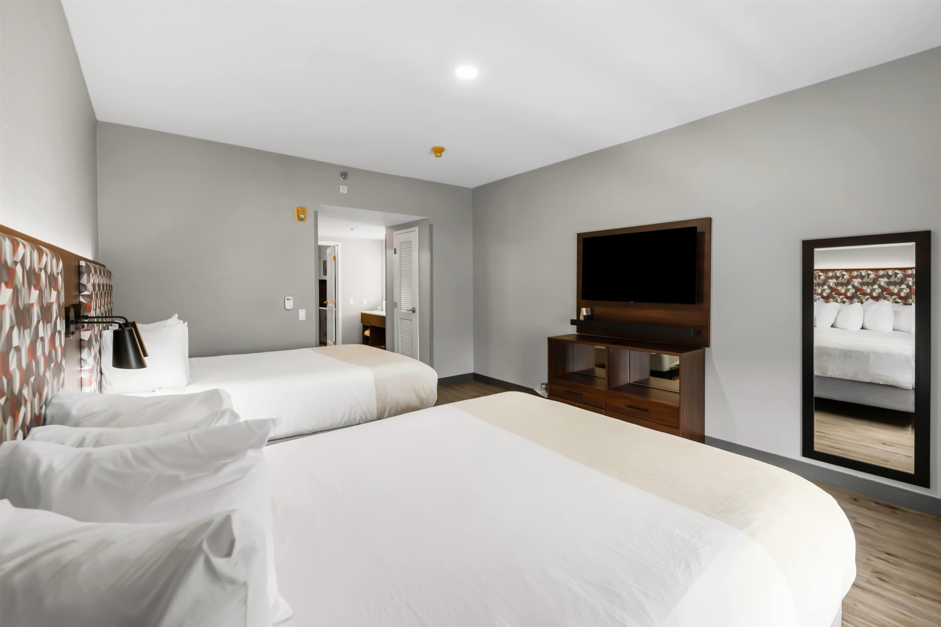 Une chambre d’hôtel avec deux lits, une télévision, un miroir et une armoire.