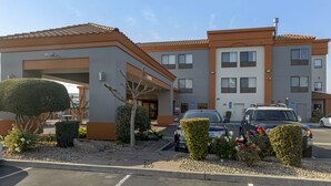 A modern building with a parking area, a covered entrance, and a small garden with trimmed bushes and flowers. - Best Western Plus Fresno Inn (Fresno)