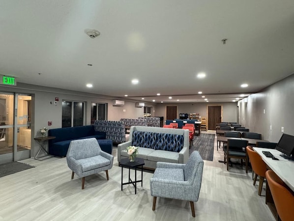 Un hall de hotel con zonas de estar, mostrador de recepción y una sala de conferencias.