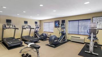 Un gimnasio con cintas de correr, elípticas y pesas sueltas.