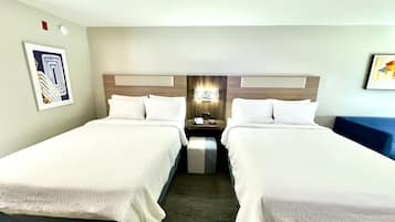 Ein Hotelzimmer mit zwei Betten, einem Nachttisch, einer Wanduhr und einem gerahmten Bild.