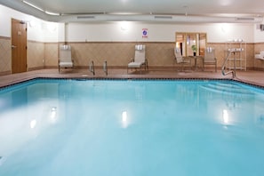 Una piscina con sillas de descanso y un letrero que indica prohibido bucear.