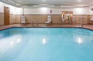 Piscina com espreguiçadeiras e placa de proibição de mergulho.