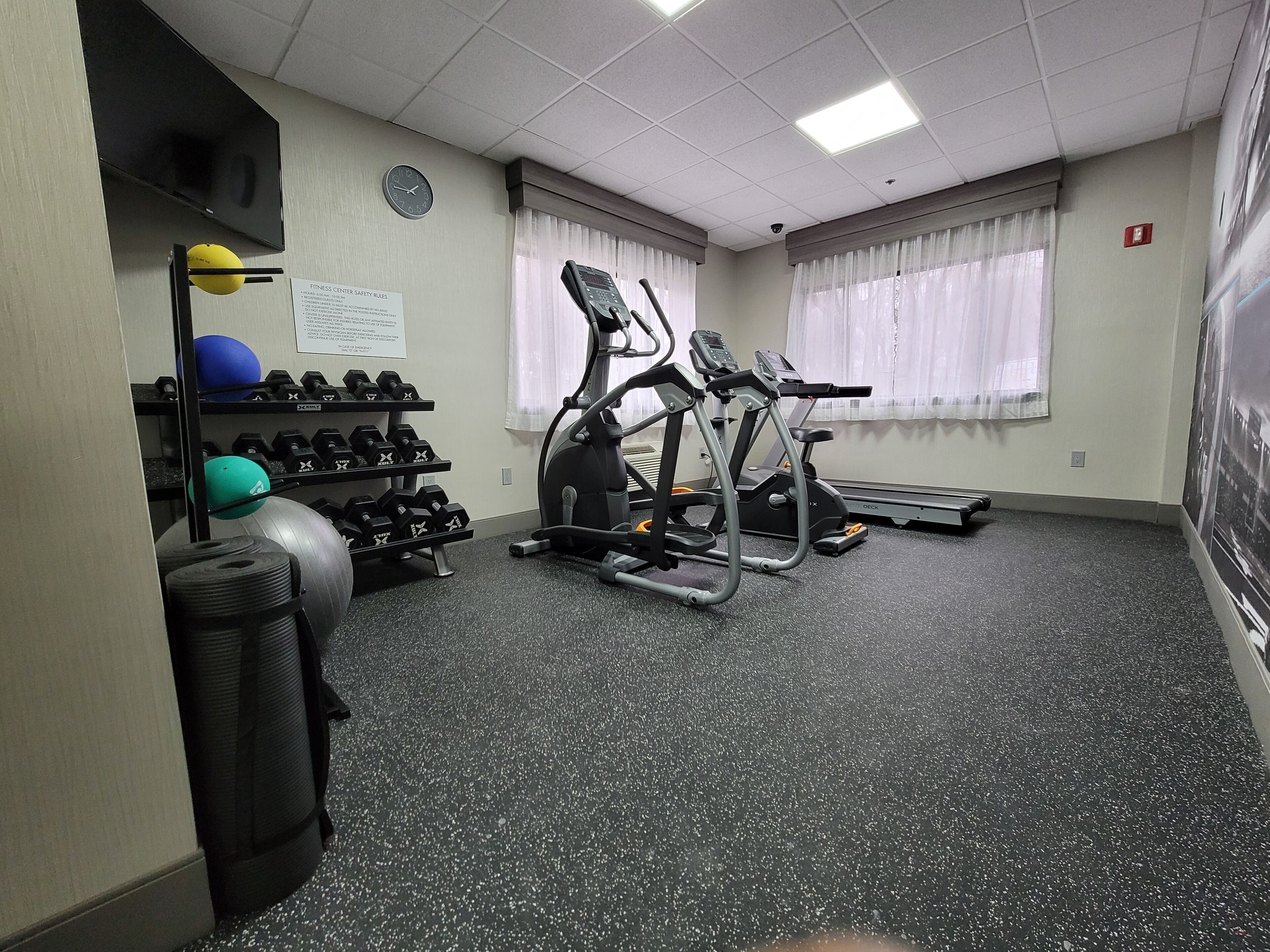 A fitness center with treadmills, dumbbells, and exercise balls.