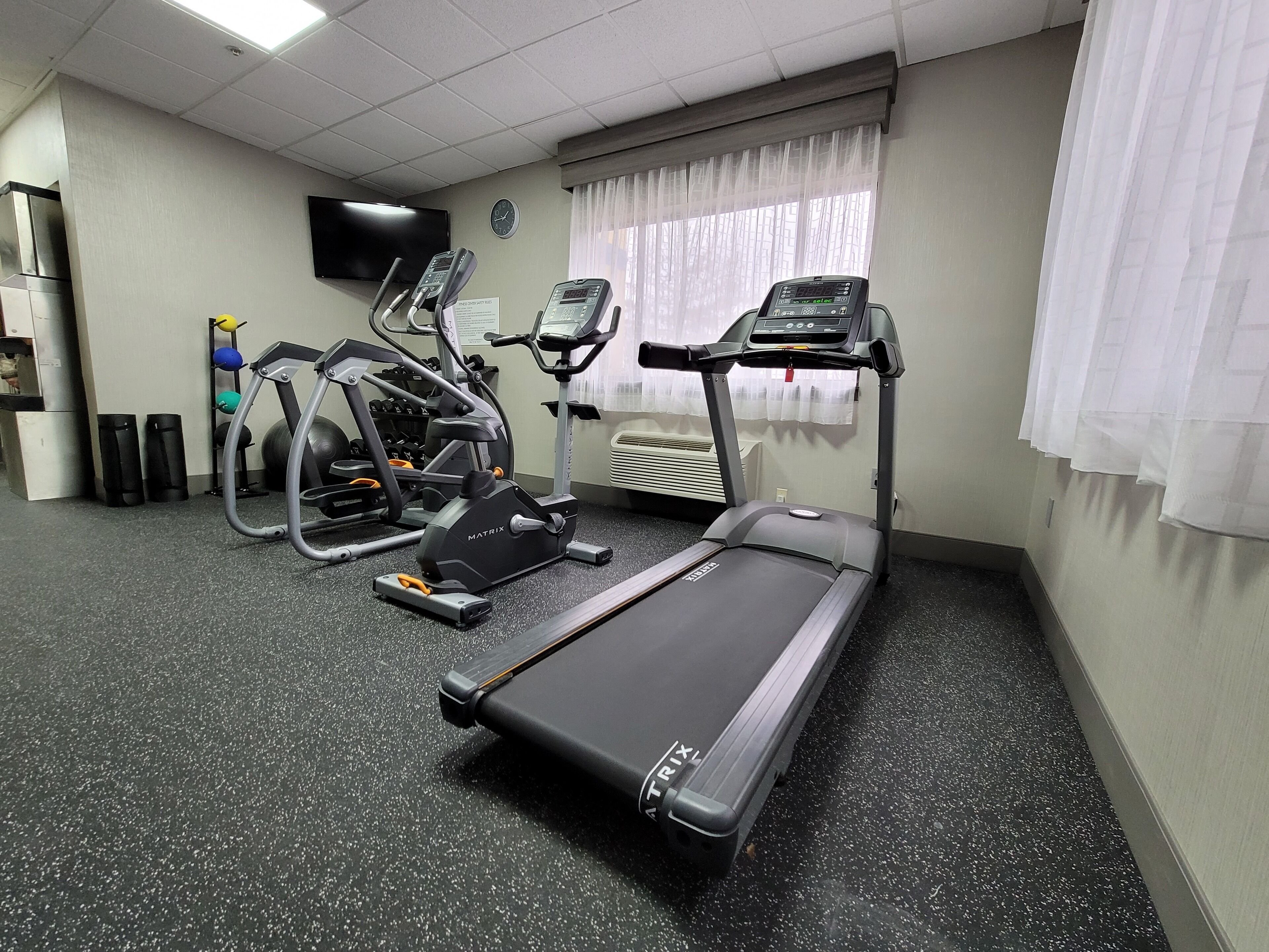 Un gimnasio con cinta de correr, elíptica y máquinas de pesas.