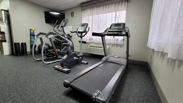 Un gimnasio con cinta de correr, elíptica y máquinas de pesas.