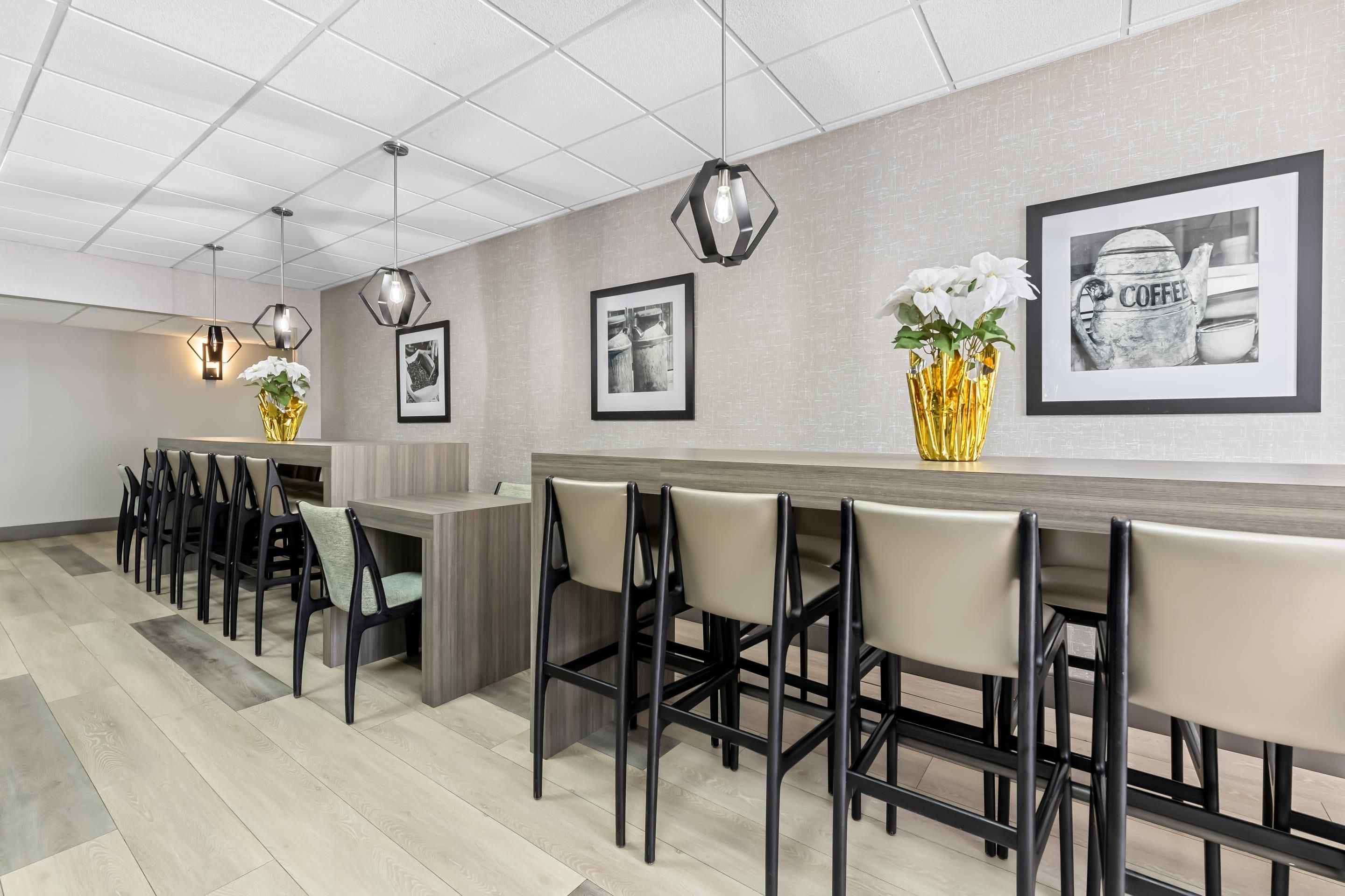 A modern bar area with hexagonal pendant lights, a long counter, and bar stools.