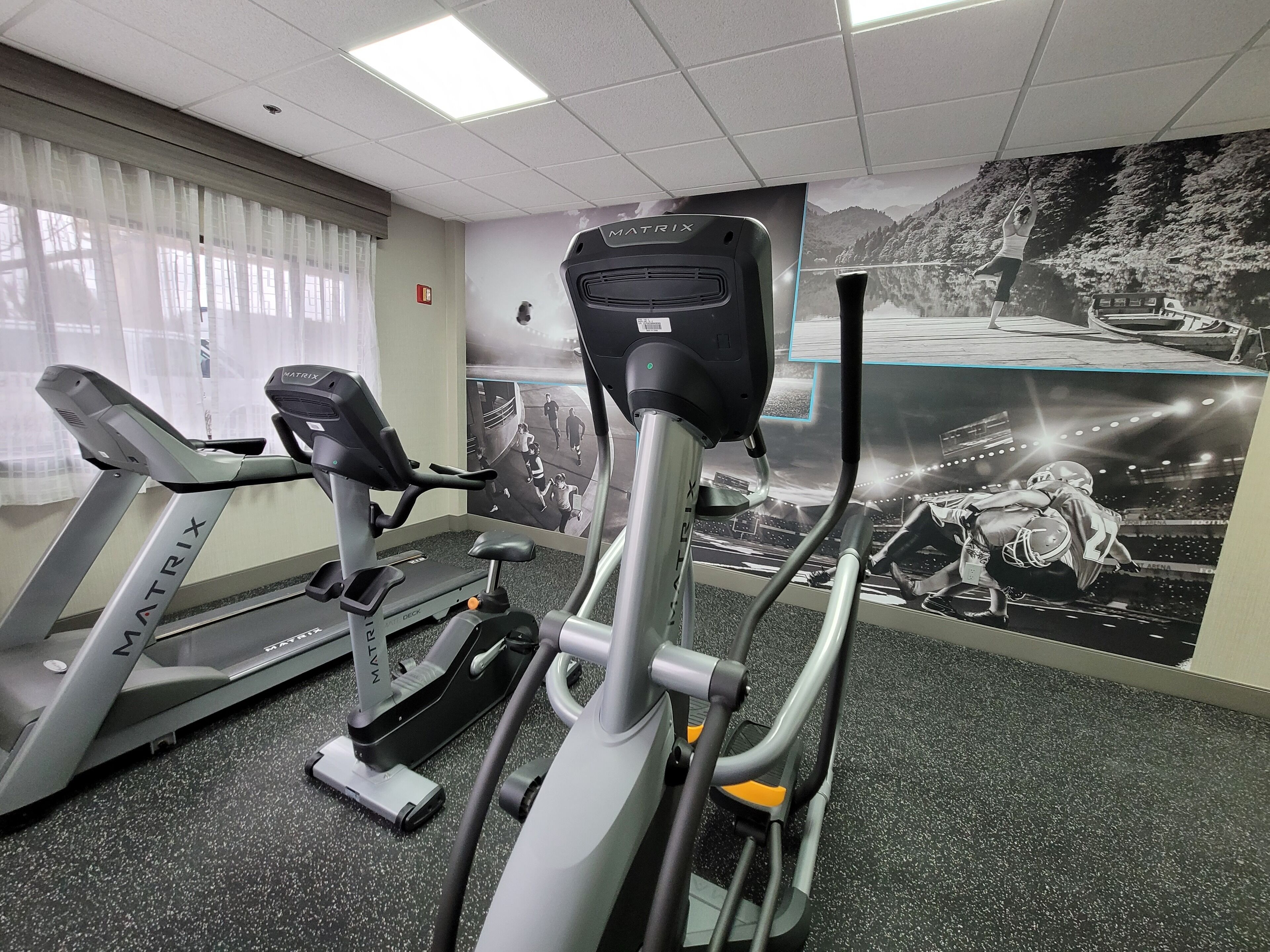 A gym with treadmills and stationary bikes, a large mirror, and a motivational poster on the wall.