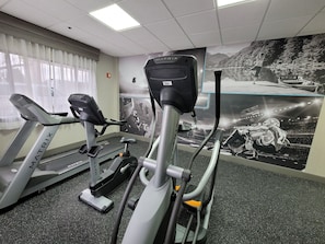 A gym with treadmills and stationary bikes, a large mirror, and a motivational poster on the wall.