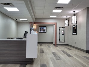 A reception area with a reception desk, a framed picture on the wall, and a mirror.