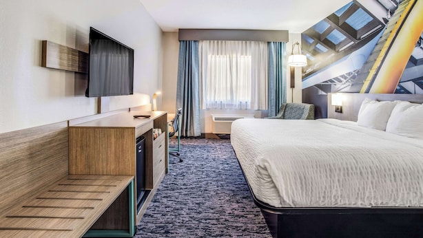 A hotel room with a bed, a desk, a chair, a TV, and a window with curtains. - Clarion Pointe Franklin - Nashville Area (Franklin)