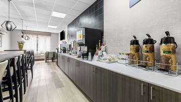 A modern kitchen with a coffee station, a dining area with chairs, and a counter with various appliances.