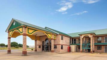 A building with a green roof, brick facade, and a covered entrance area.