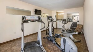 Une salle de remise en forme équipée de tapis de course, d’un vélo elliptique et d’un vélo d’appartement.