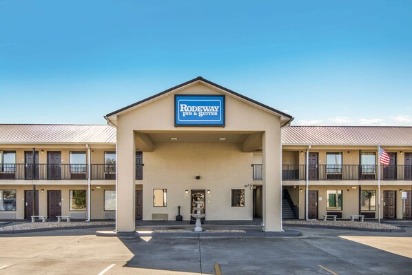A Rodeway Inn & Suites with a central entrance, multiple balconies, and an American flag.