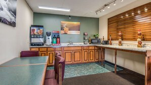 Une cuisine équipée d’une table à manger, de chaises, d’une machine à café, d’un four à micro-ondes et d’un meuble en bois.