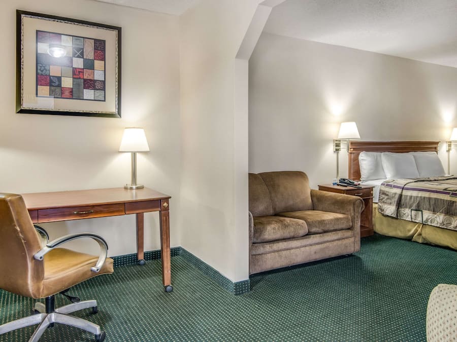A hotel room with a desk, chair, sofa, and bed.