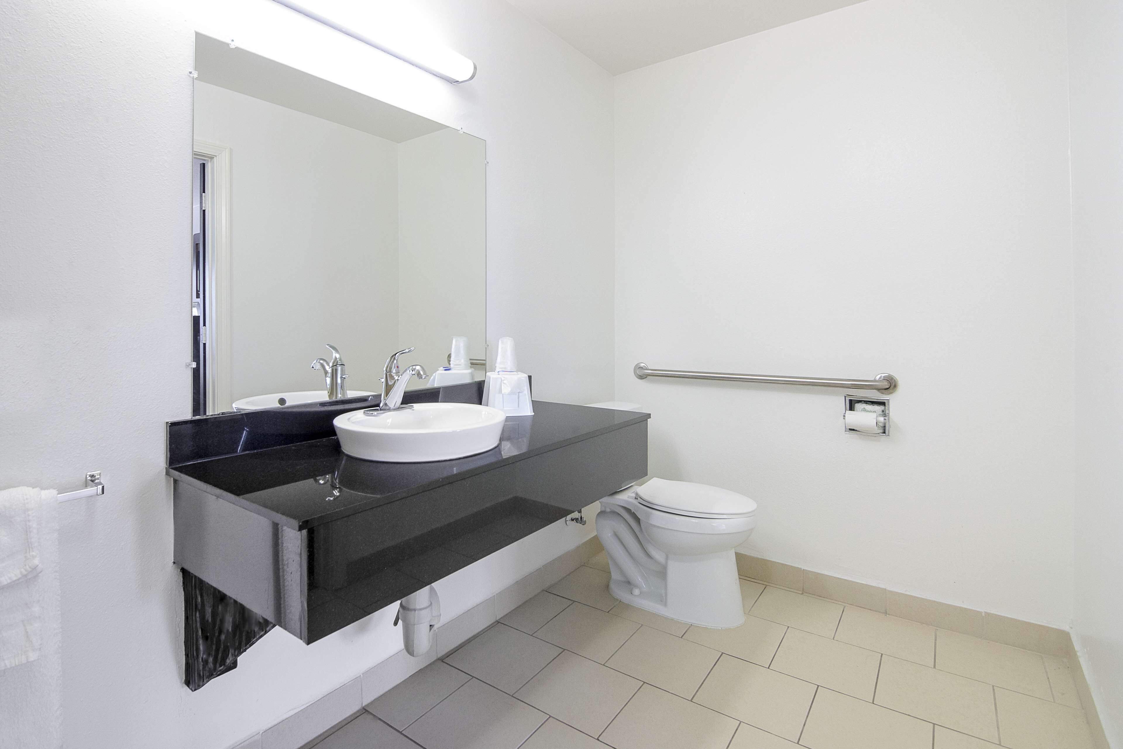 A modern bathroom with a black countertop, white sink, and a mirror above it.