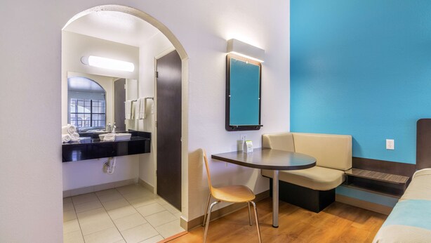 A compact hotel room with a kitchenette, a small dining table, a chair, and a bed. - Motel 6 Canton, TX (Canton)