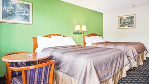 A hotel room with two beds, a round wooden table, and two chairs. - Economy Inn by OYO Ashburn I-75 (Ashburn)