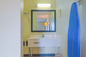 A bathroom with a white sink, mirror, and blue shower curtain. - Economy Inn by OYO Ashburn I-75 (Ashburn)