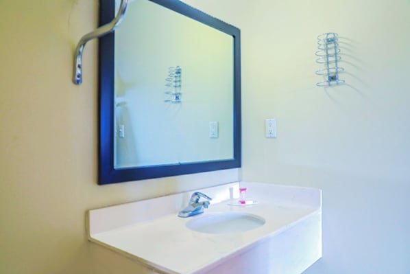 A bathroom with a white sink, a mirror, and a towel rack. - Economy Inn by OYO Ashburn I-75 (Ashburn)