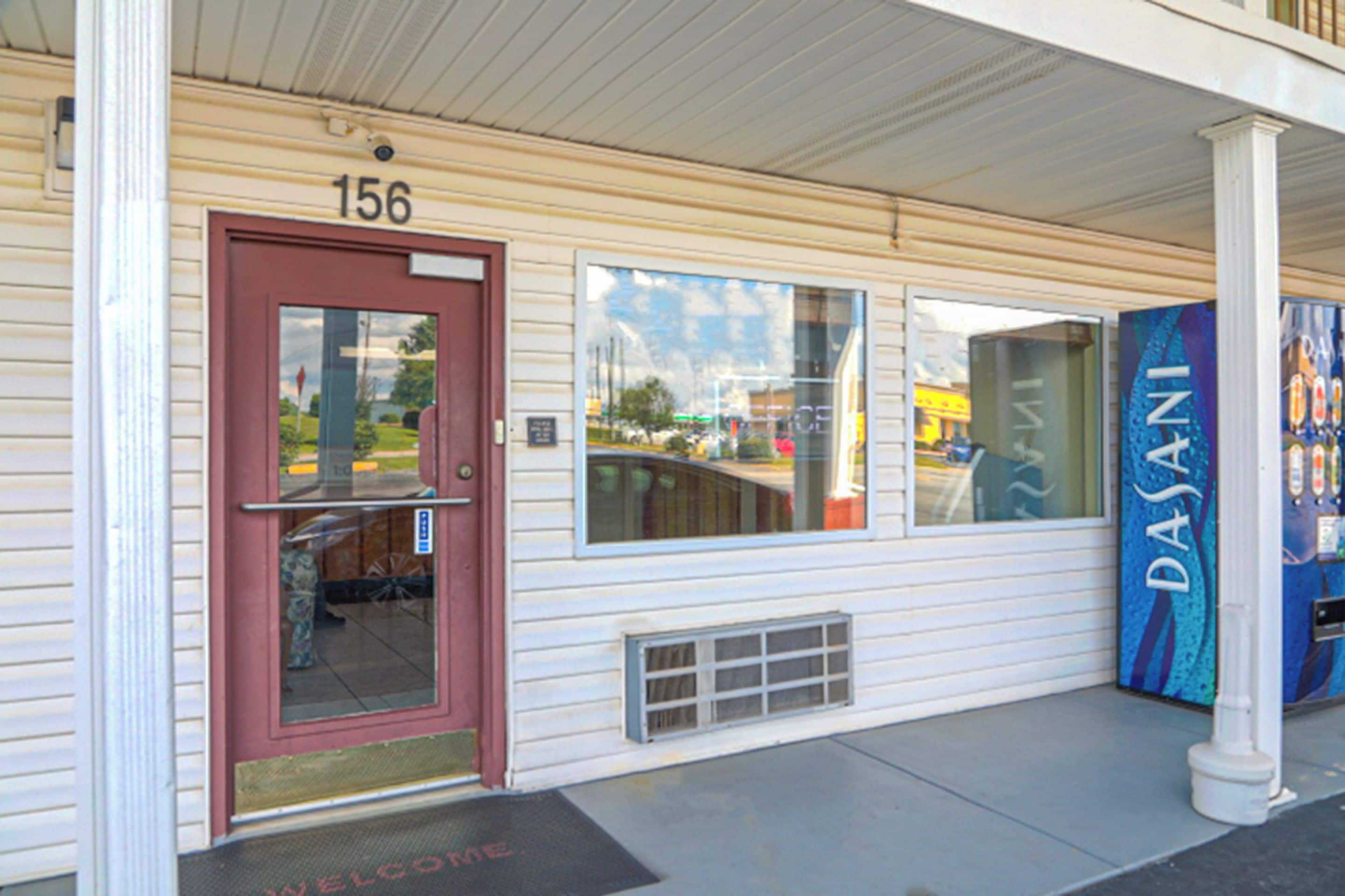 A building with a red door, a number 156 sign above it, and a blue sign with the text "DASANI" on the right.