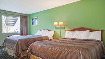 Habitación de hotel con dos camas, una ventana con cortinas, un cuadro en la pared y una mesita de noche con lámparas.