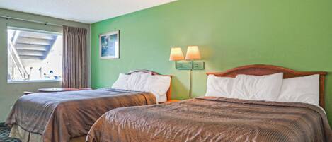 A hotel room with two beds, a window with curtains, a painting on the wall, and a nightstand with lamps.