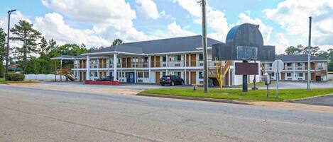 A motel with a large parking lot, a covered outdoor seating area, and a prominent dome-shaped building.