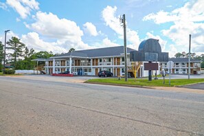 A motel with a large parking lot, a covered outdoor seating area, and a prominent dome-shaped building. - Economy Inn by OYO Ashburn I-75 (Ashburn)