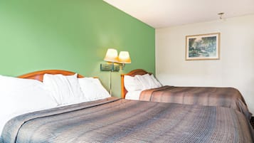 A hotel room with two beds, a green wall, a painting, and a nightstand with lamps.