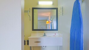 A bathroom with a white sink, mirror, and blue shower curtain. - Economy Inn Ashburn GA I-75 (Ashburn)