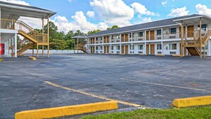 A motel with a central parking lot, multiple-story buildings, and a covered walkway. - Economy Inn by OYO Ashburn I-75 (Ashburn)