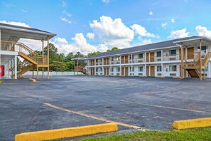 A motel with a central parking lot, multiple-story buildings, and a covered walkway. - Economy Inn by OYO Ashburn I-75 (Ashburn)