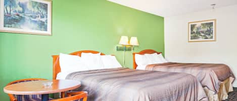 A hotel room with two beds, a round wooden table, and two chairs.