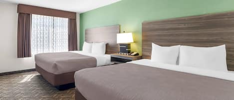 A hotel room with two beds, a nightstand with a lamp, and a window with curtains.