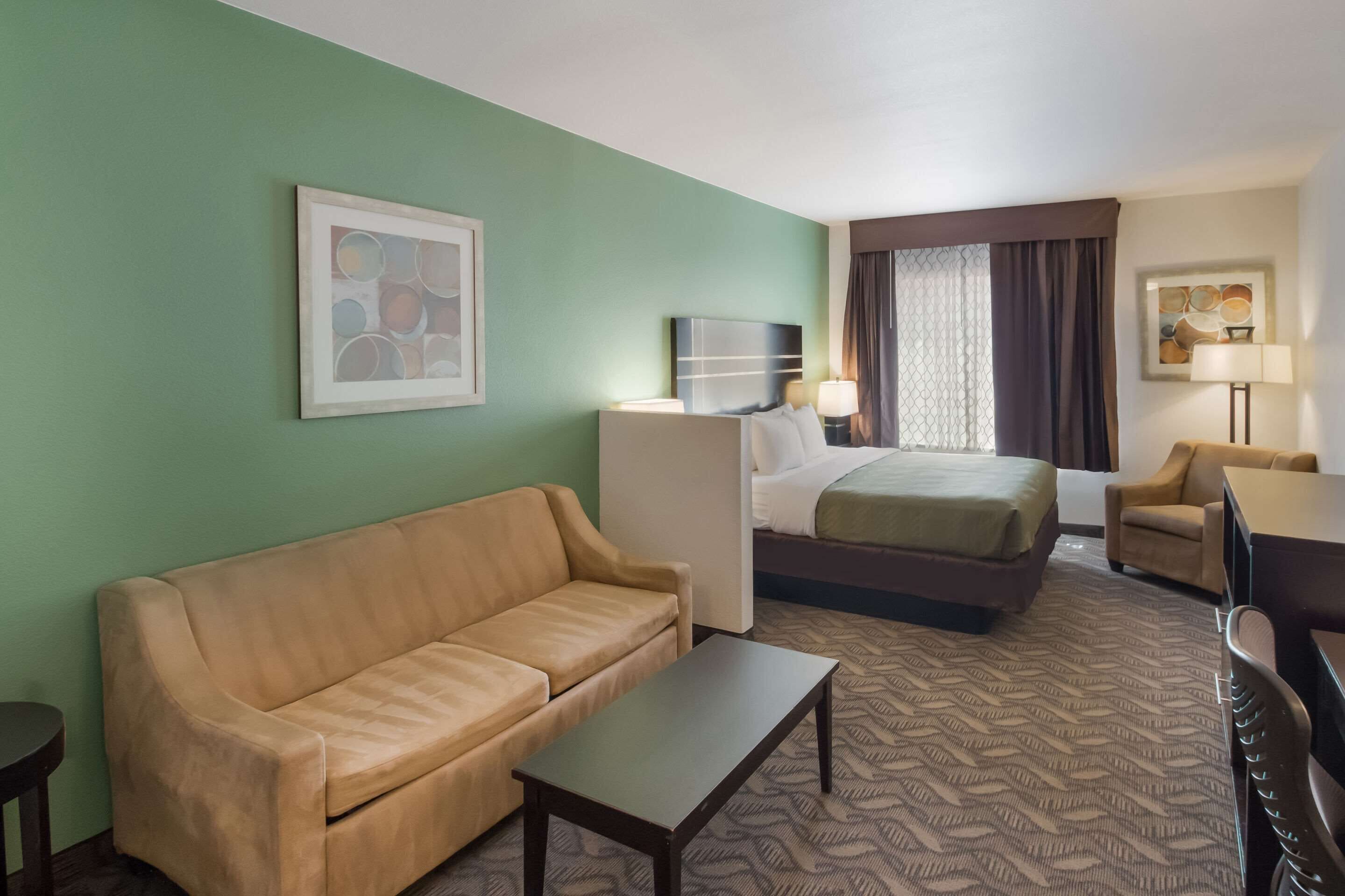 A hotel room with a bed, a sofa, a coffee table, and a desk.