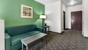 Une pièce avec un mur vert, un canapé, une petite table, une lampe et un tapis à motifs.