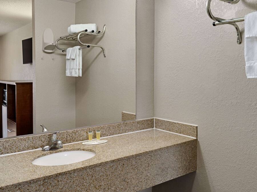 Un baño con lavamanos de encimera de granito, un espejo y un perchero para toallas.
