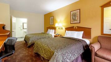 A hotel room with two beds, a desk, a chair, and a nightstand with a lamp.
